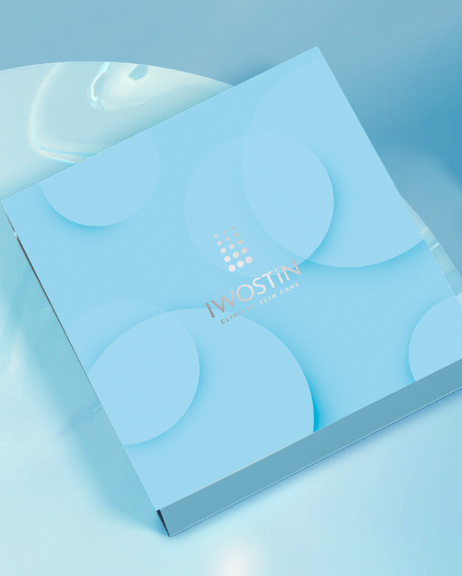 Iwostin opakowanie prezentowe - niebieskie opakowanie w kształcie kwadratu, logo Iwostin w srebrze na środku opakowania; całość na niebieskim tle, widok od gory